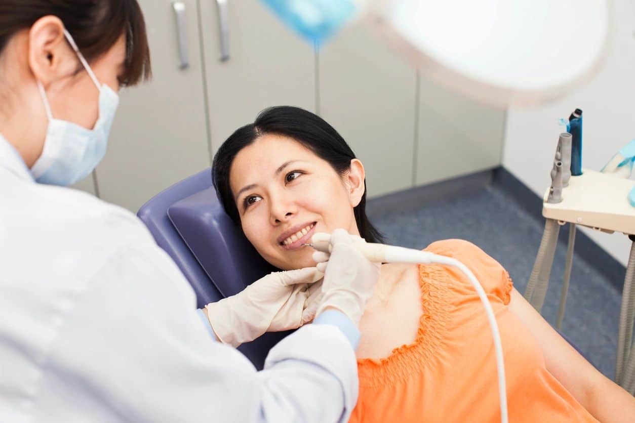 a dentist using a tool on a woman's mouth