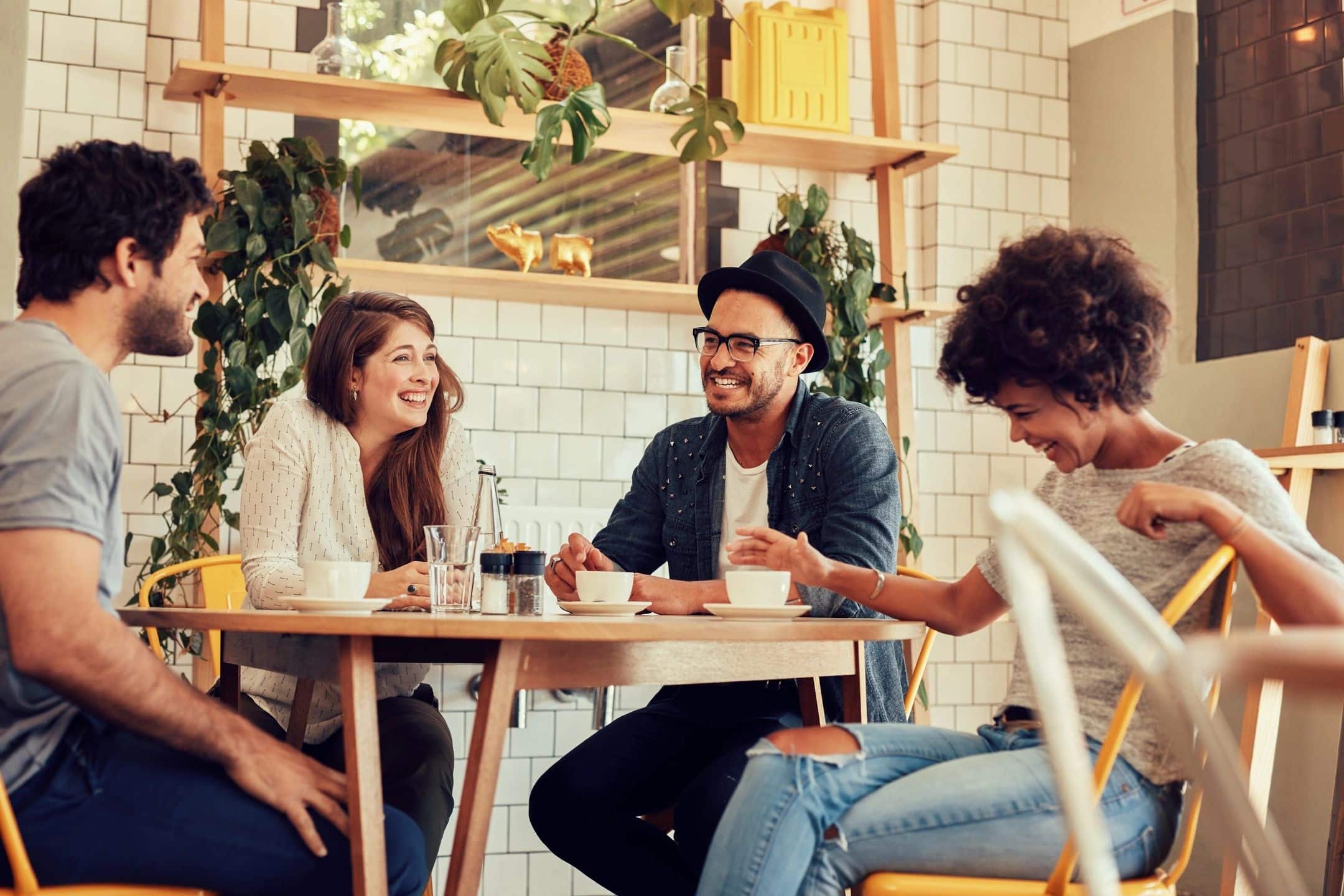 Four people laughing sitting around a table having coffee