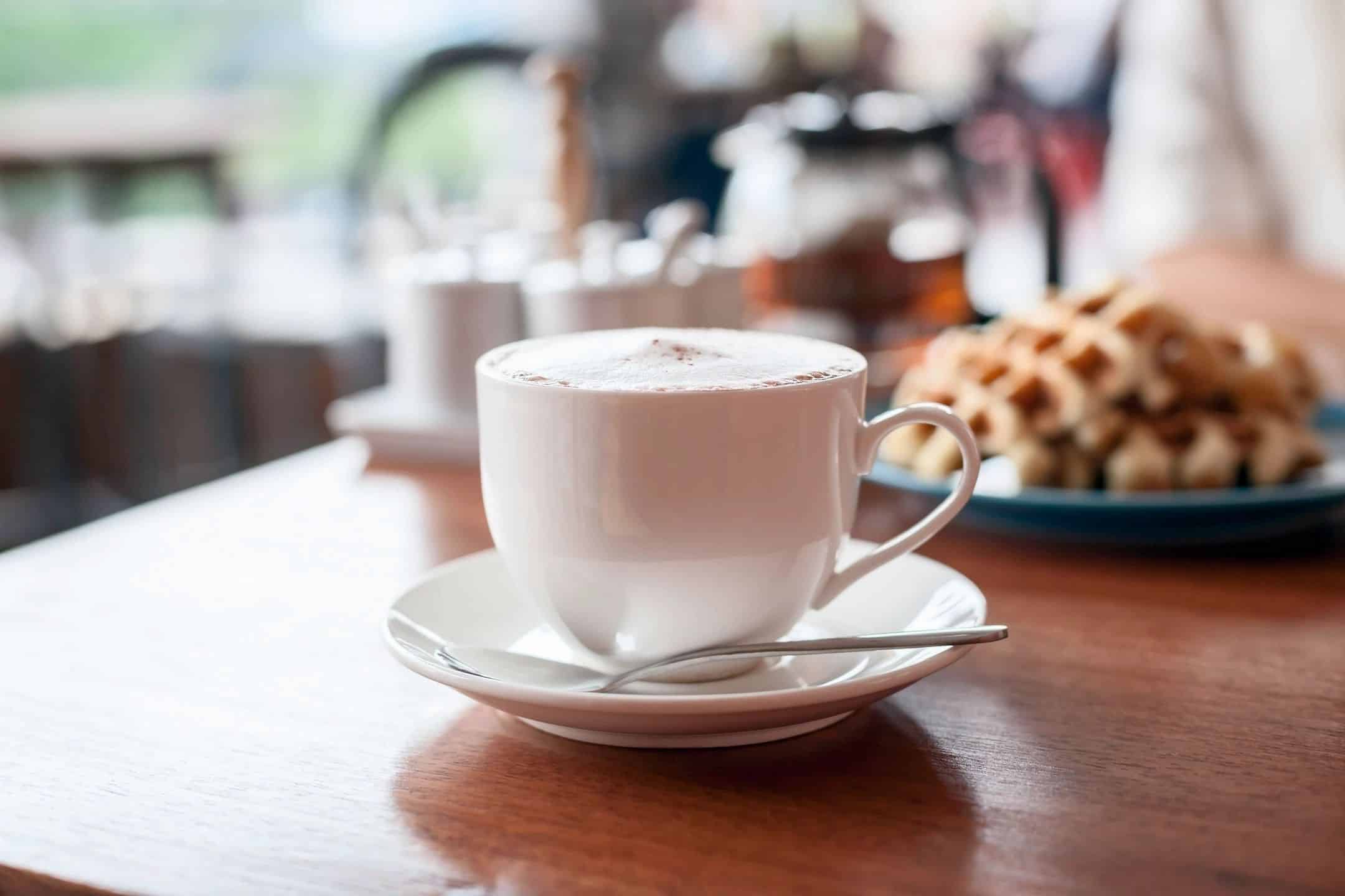 Cup of coffee with pastry in the background