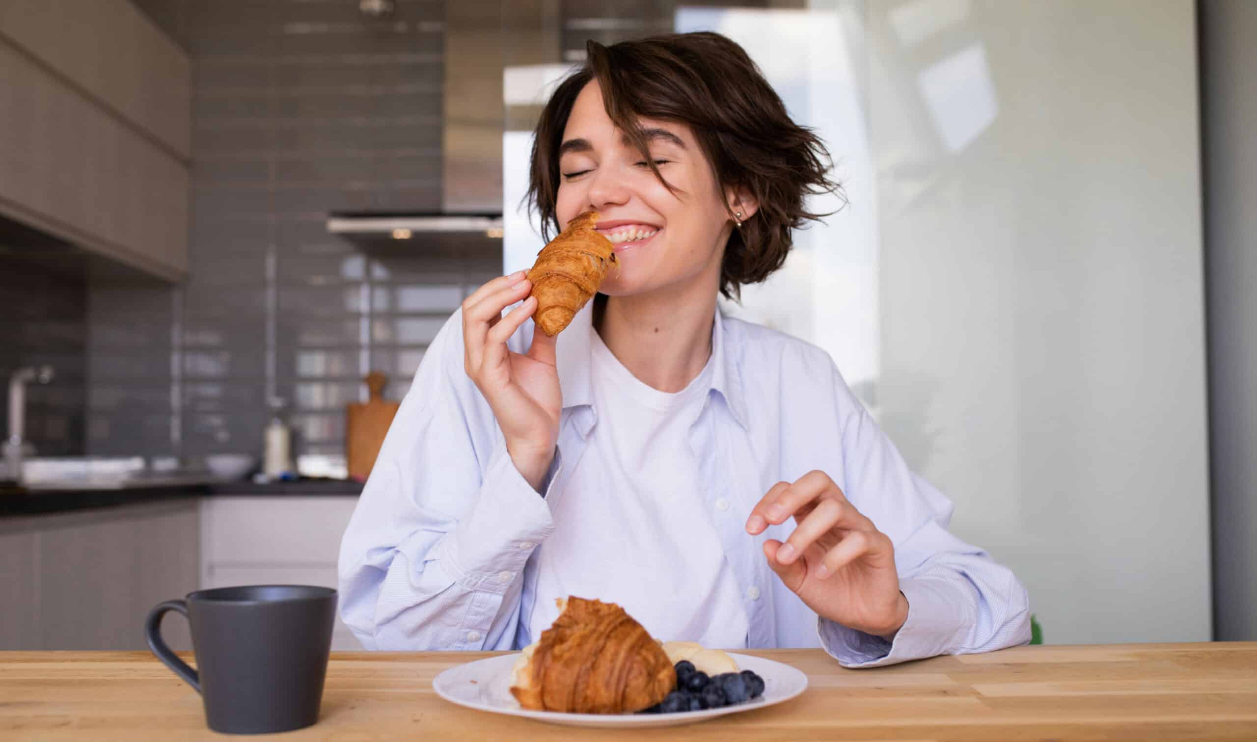 A woman enjoying a croissant for breakfast