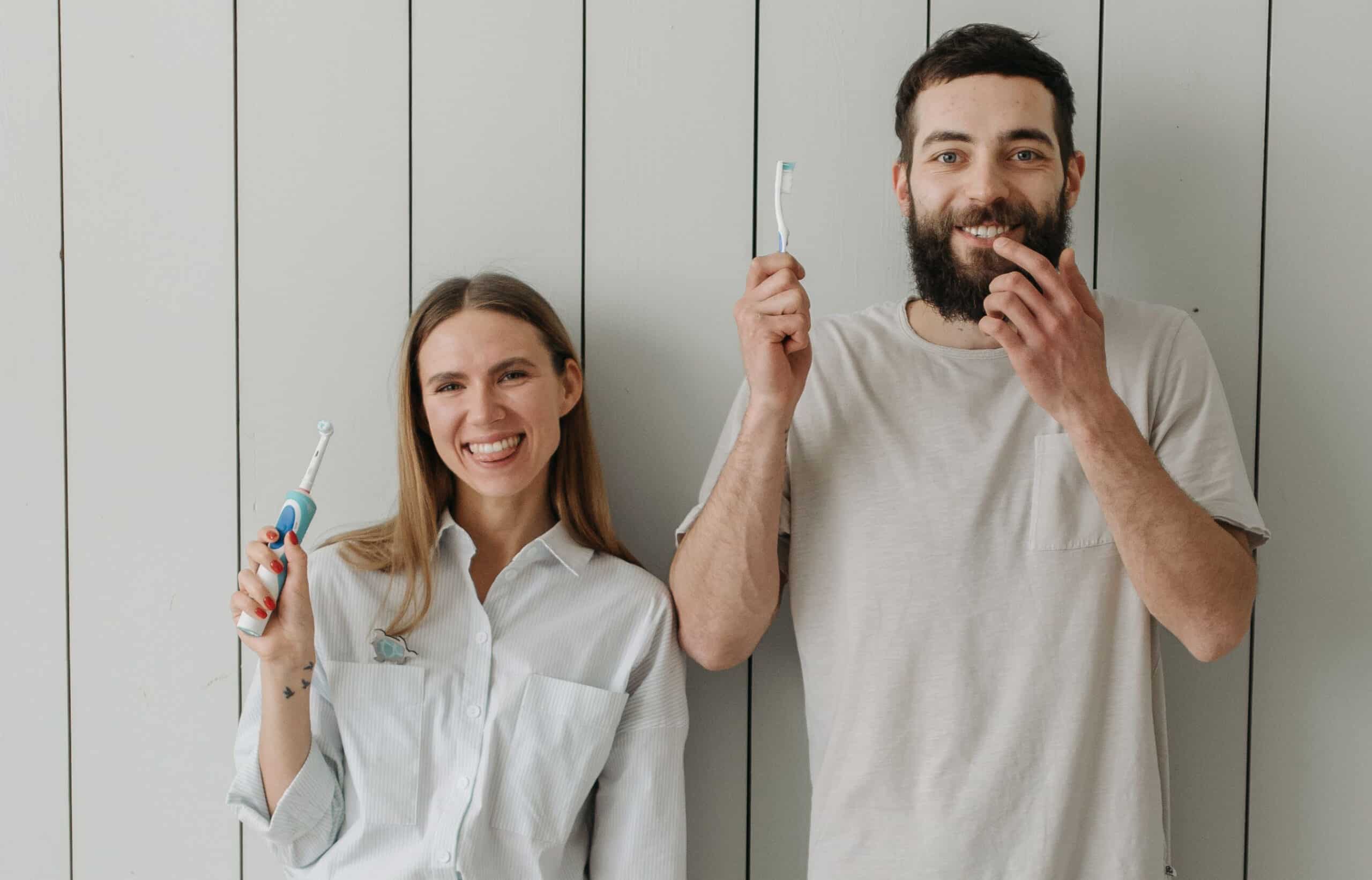 Two people with electric vs manual toothbrush