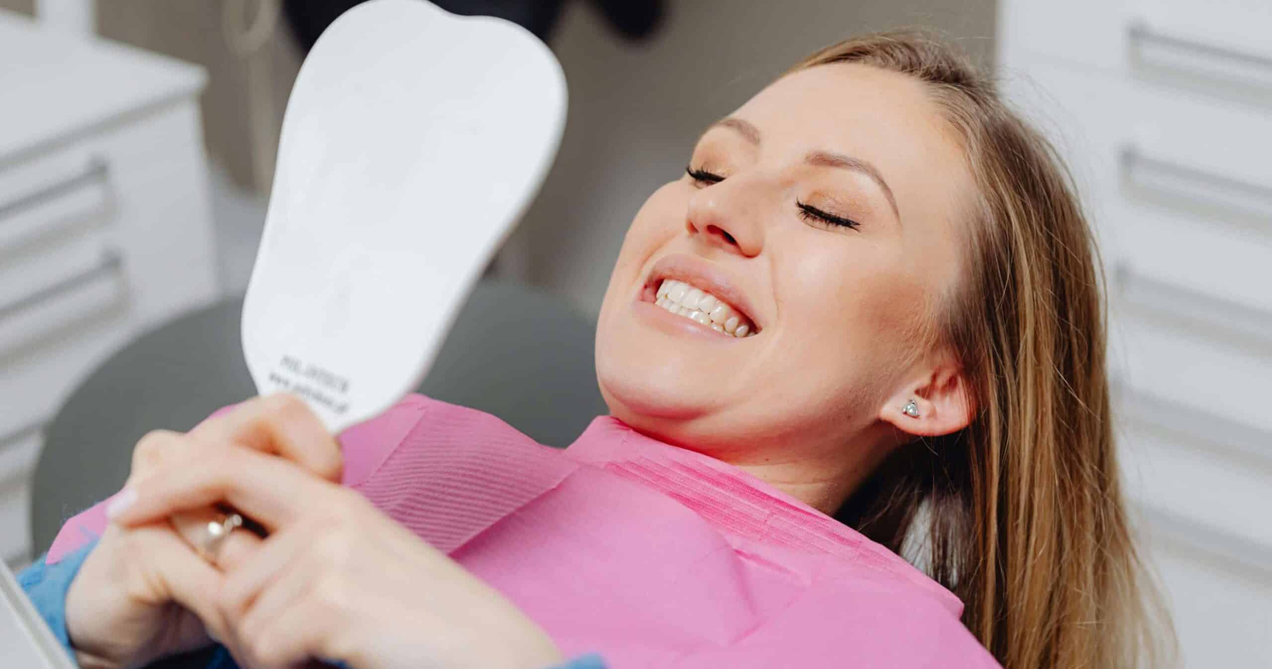A woman looking at her white teeth in the mirror
