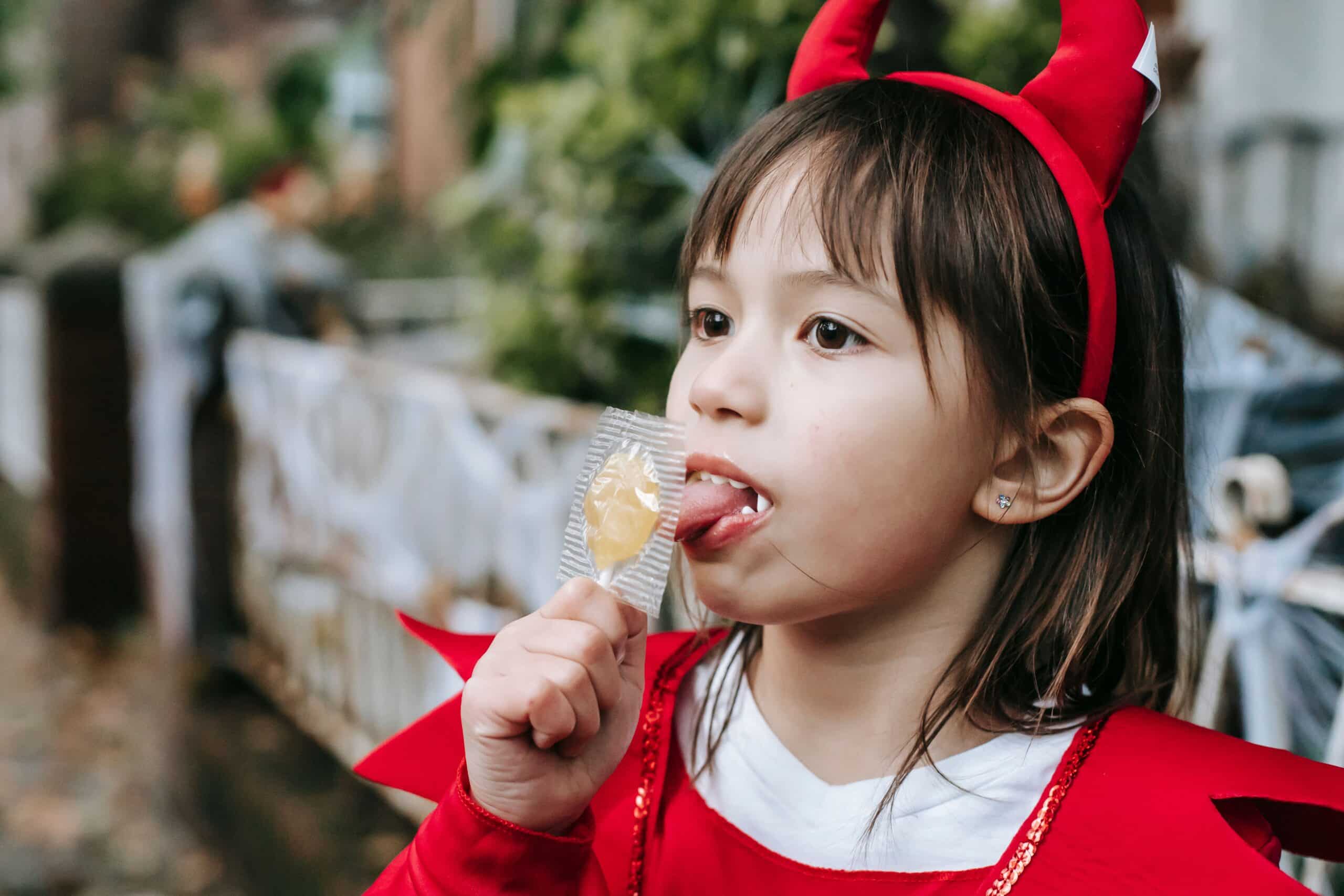 Little girl in a devil costume with a sucker